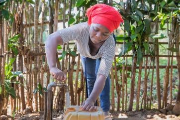 A farmer gets water from a prosper global water tap near their home.