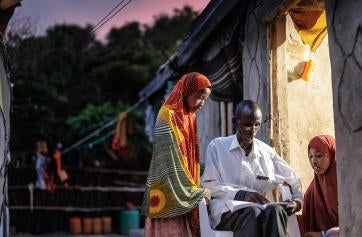 A father and his two daughters read by light at night. 