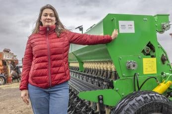 Ukrainian woman stands next to new agricultural implement.
