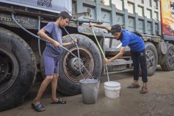 Two palestinian boys gather water from tender truck.