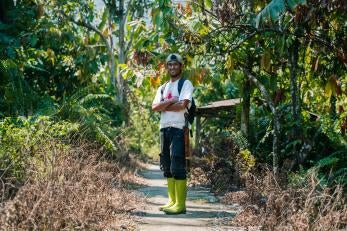 Marwan stands among cocoa trees on his farm in Indonesia.