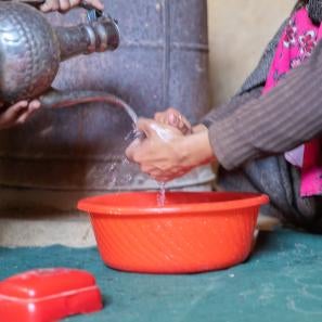 Washing hands in a basin.