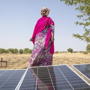 Nigerian woman standing behind a solar panel.