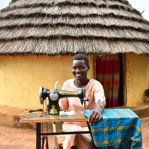 A girl-h participant poses with a tailoring machine she purchased through her participation in the girl-h financial inclusion interventions.
