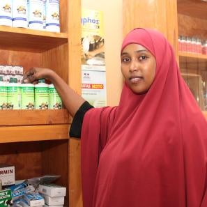 Woman from horn of africa displays some products in her agrovet shop.