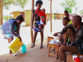 A group of people watch a person pour milk into a pitcher.